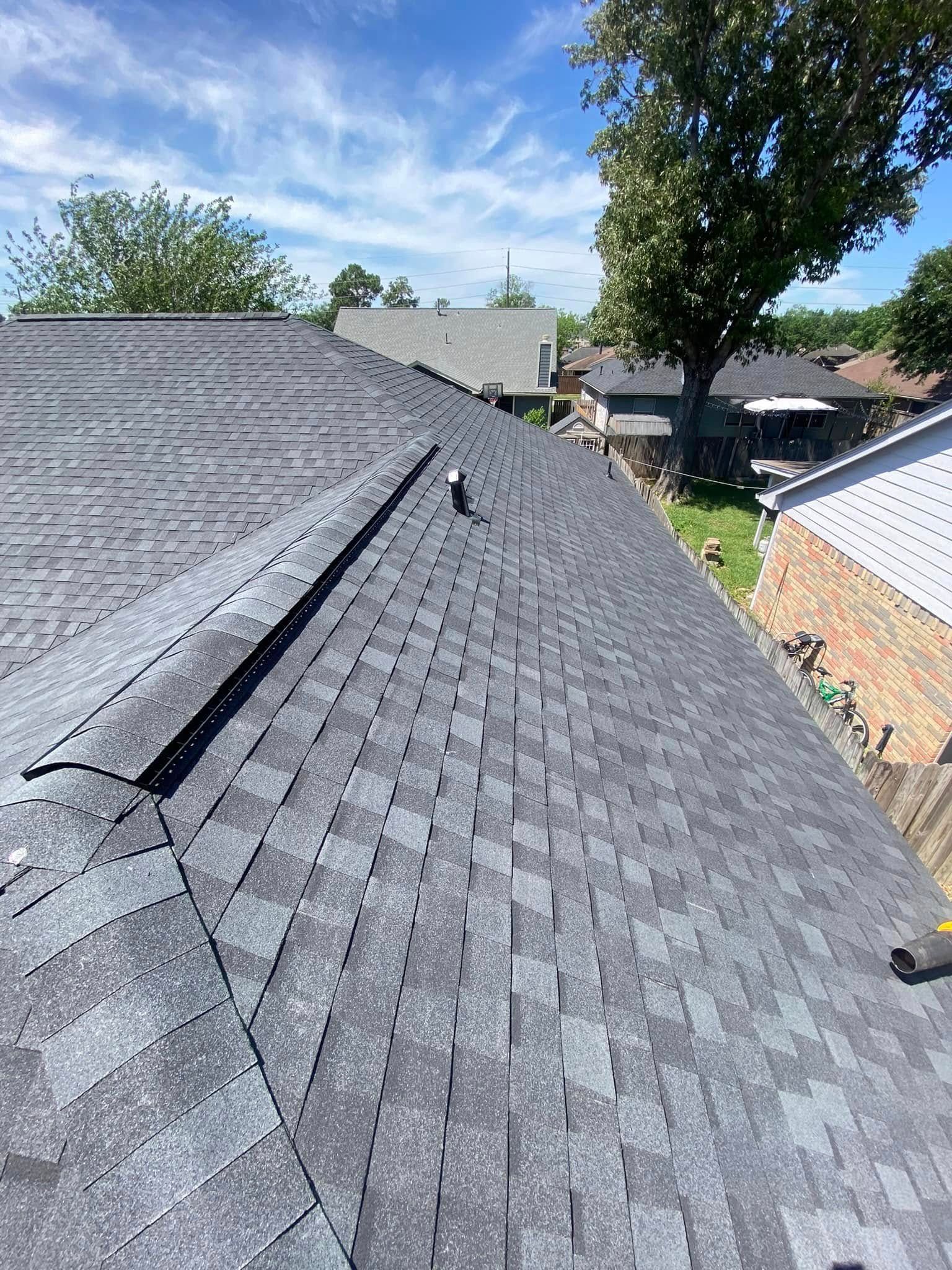 Newly installed gray asphalt shingle roof on a sunny day.