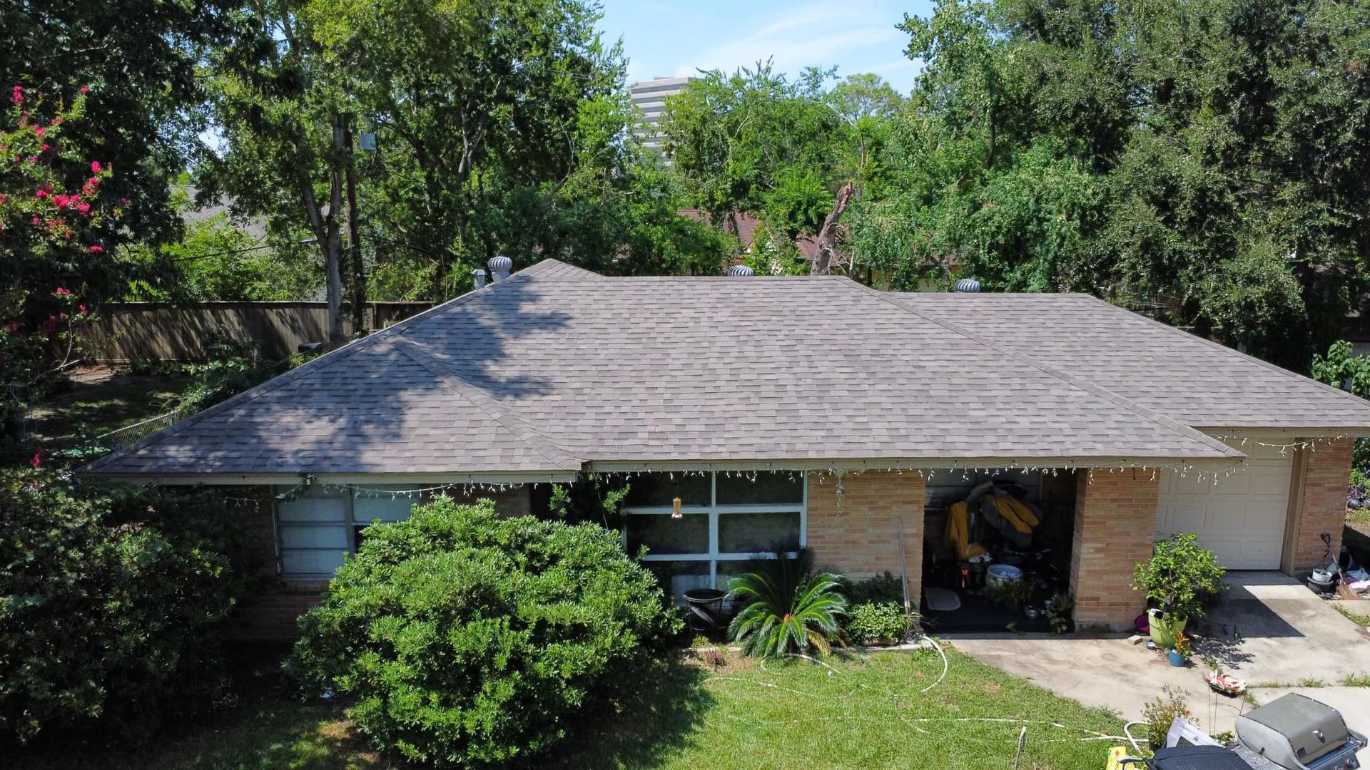 Brown-roofed house with brick facade and green lawn. Trees in the background.