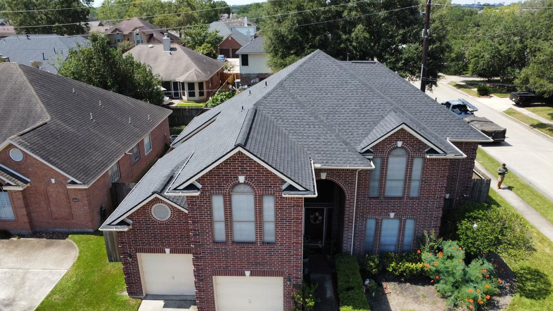 Brick house with dark roof and two-car garage in a suburban neighborhood.