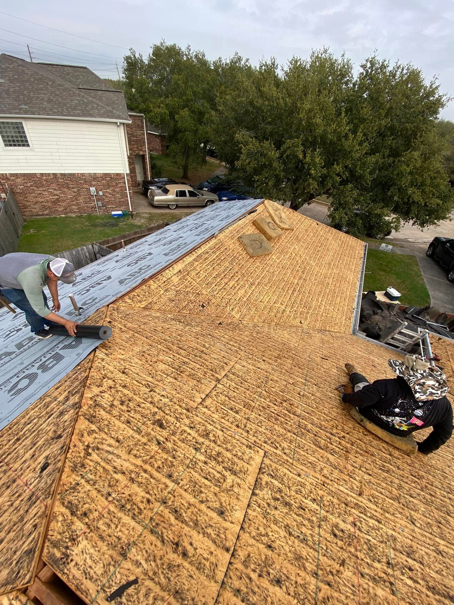 Roofers installing shingles on a residential roof; cloudy day.