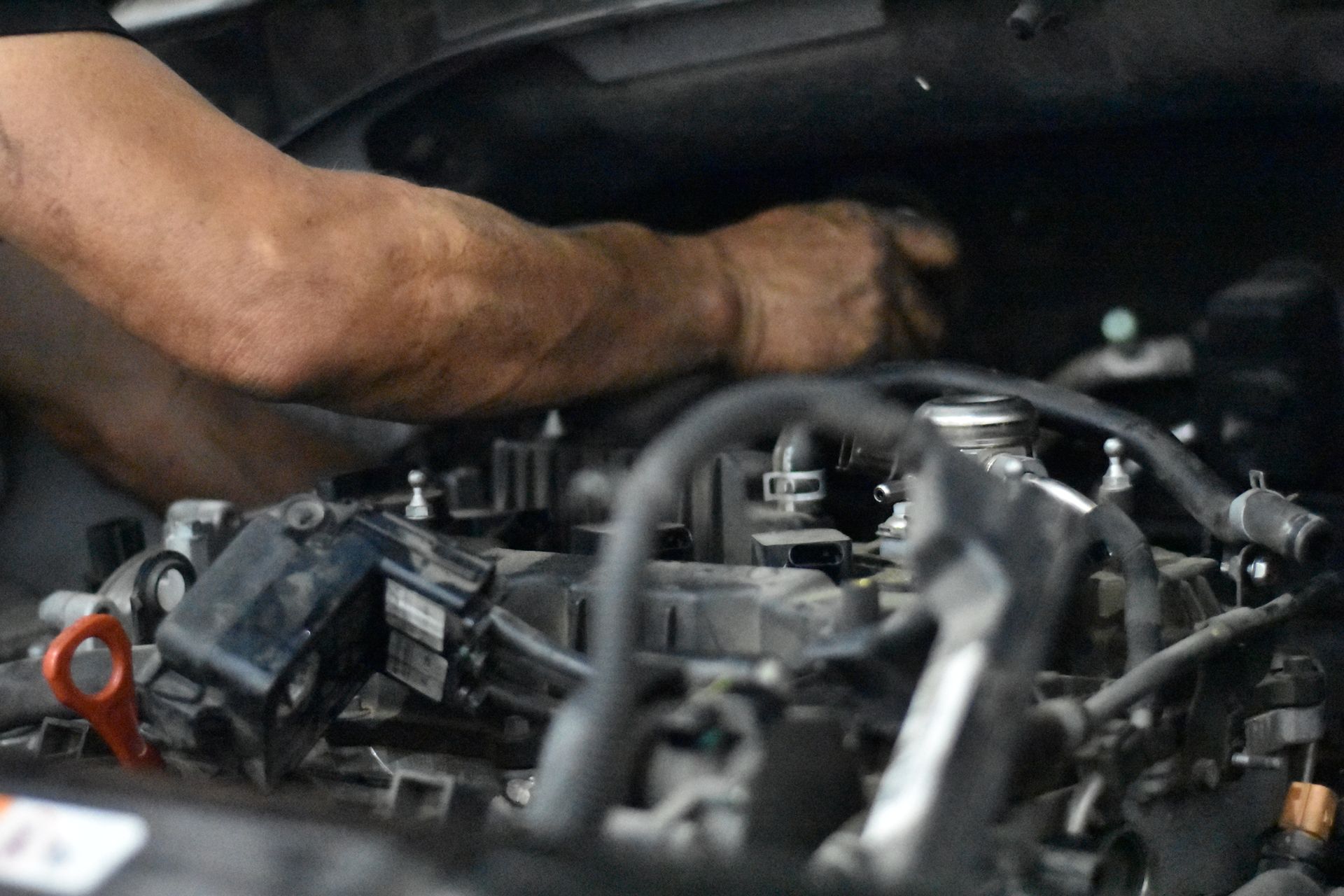 Mechanic's hands working on a car engine, reaching into the engine bay.