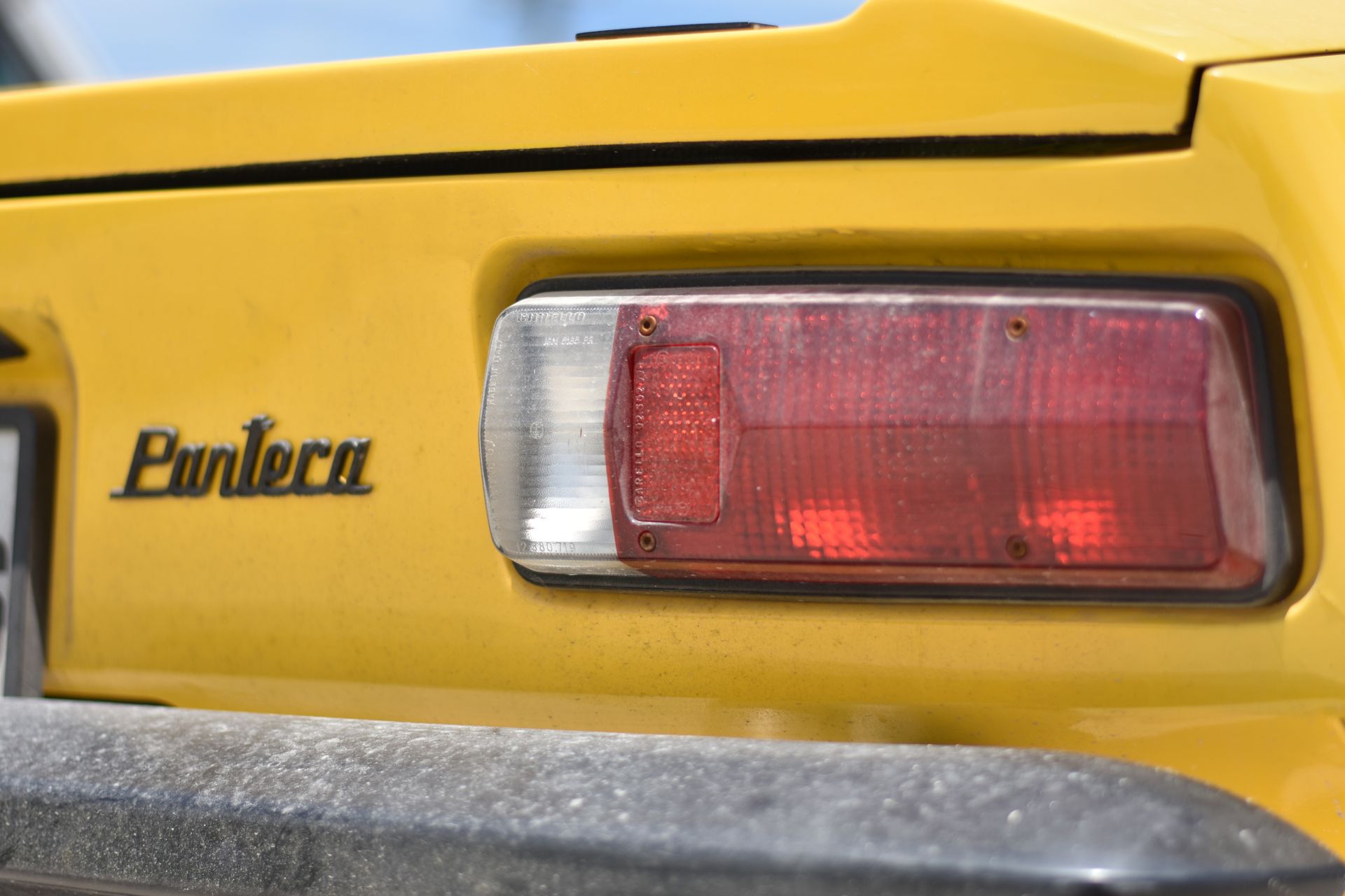 Yellow De Tomaso Pantera car rear with Pantera logo and taillight.