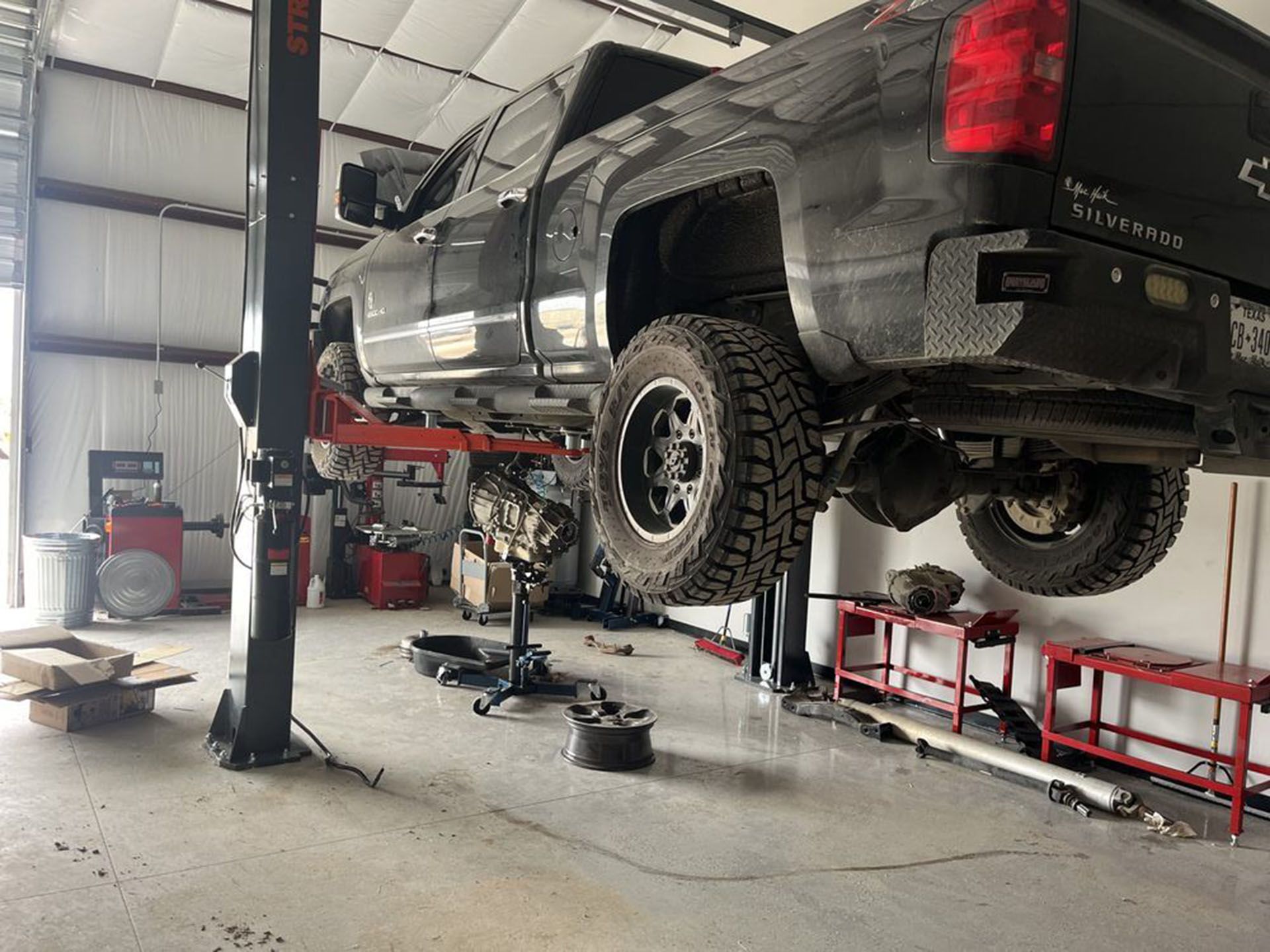 A truck is sitting on a lift in a garage.