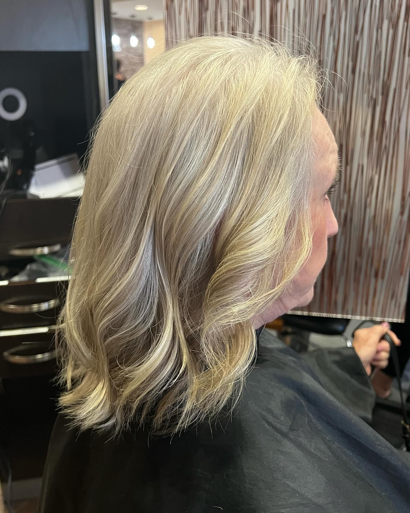 A woman with blonde hair is getting her hair cut in a salon.