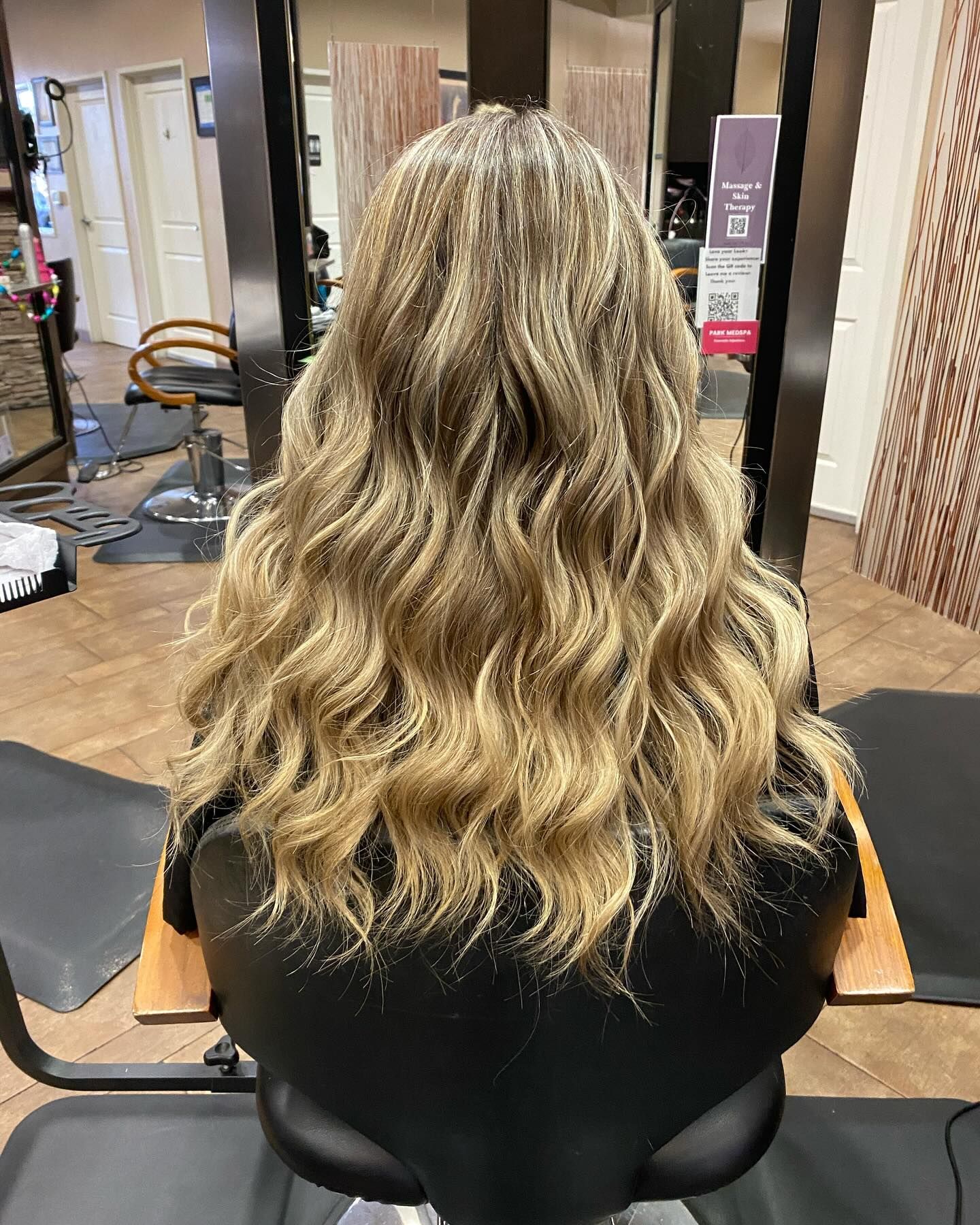 A woman is sitting in a chair with her hair in a salon.
