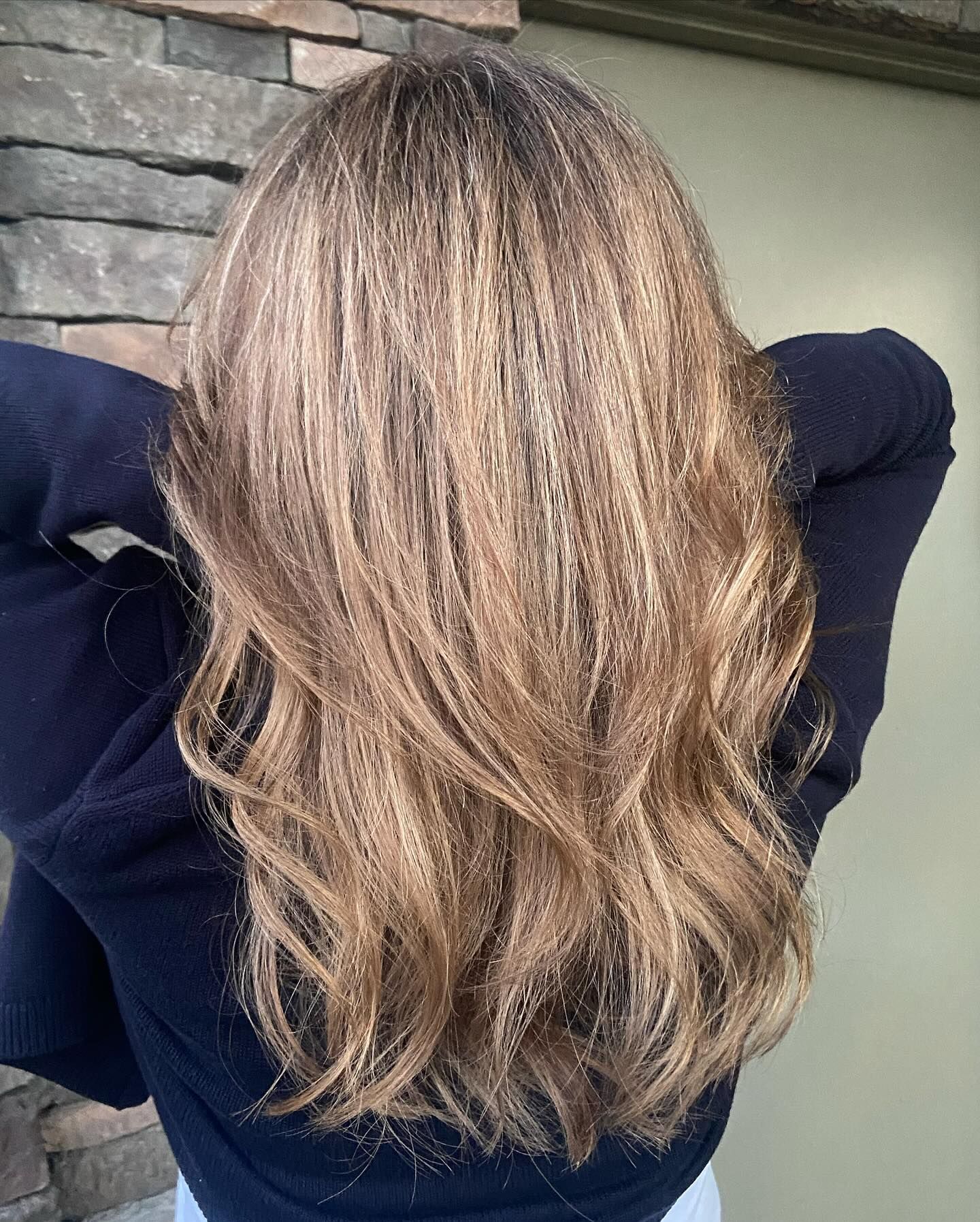 A woman with long blonde hair is wearing a black sweater.