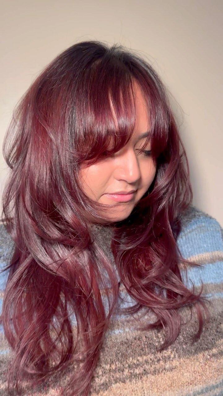 A woman with long red hair and bangs is wearing a blue sweater.