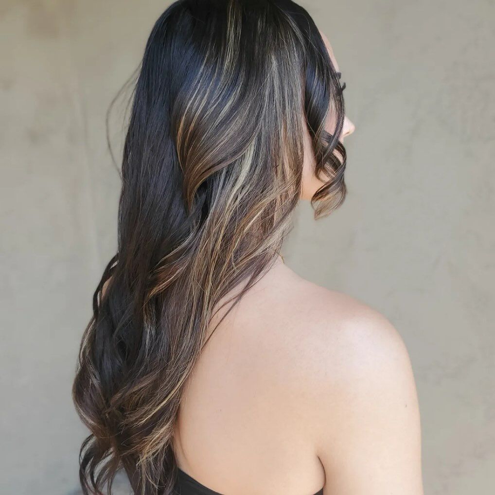 A woman with long dark hair is wearing a black top