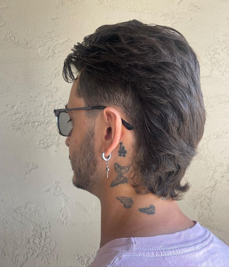 A man with a mohawk and a tattoo on his neck