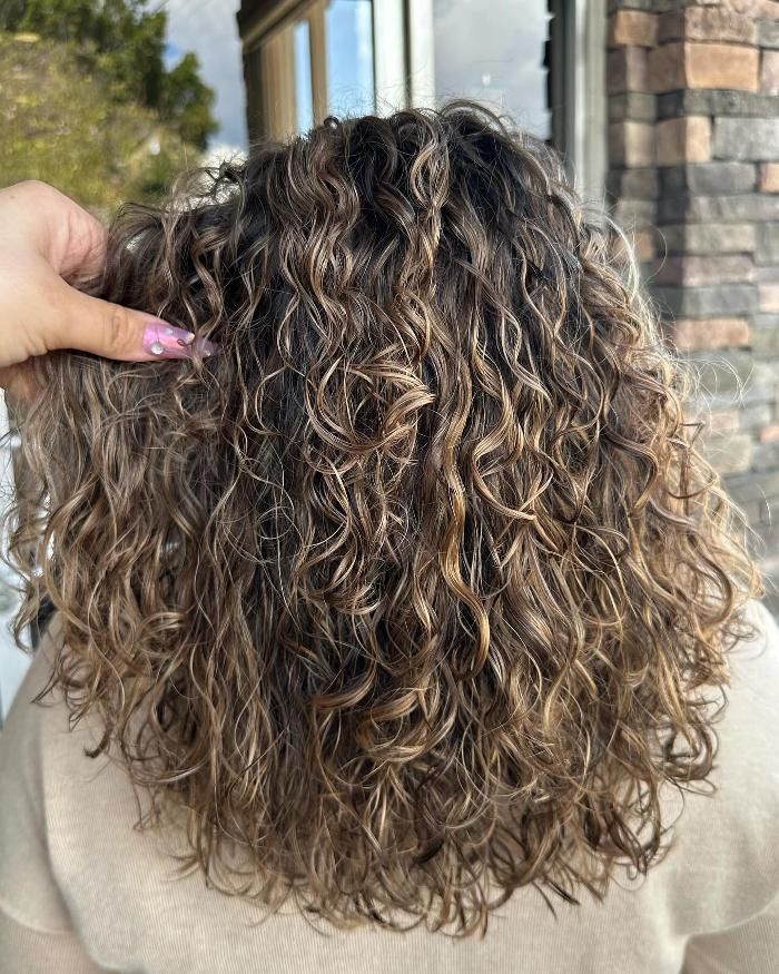 A person is touching a woman 's curly hair.