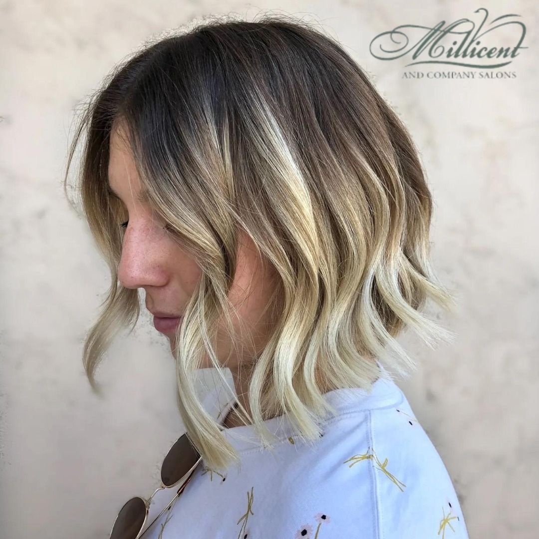 A woman with short blonde hair is wearing a white shirt.