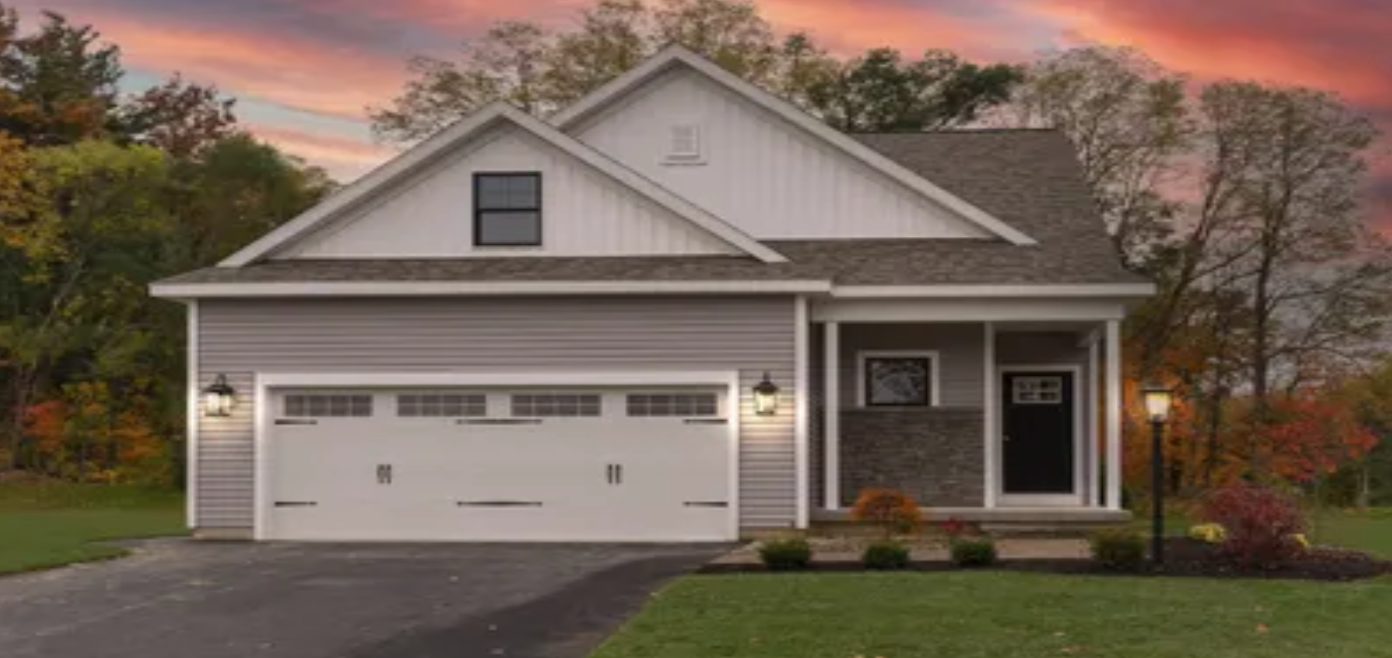 A single-family house with a garage and covered entrance in an autumn landscape.