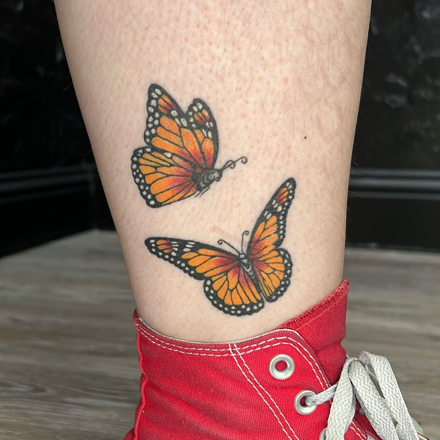 A person has two butterflies tattooed on their ankle.