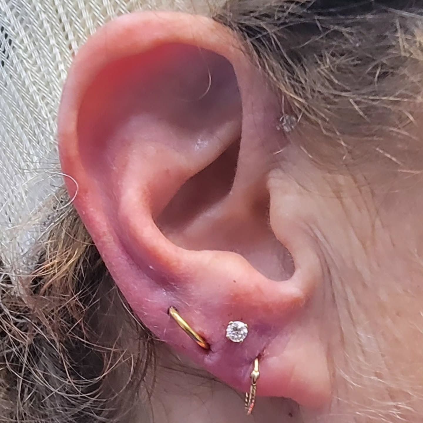 A close up of a person 's ear with multiple piercings