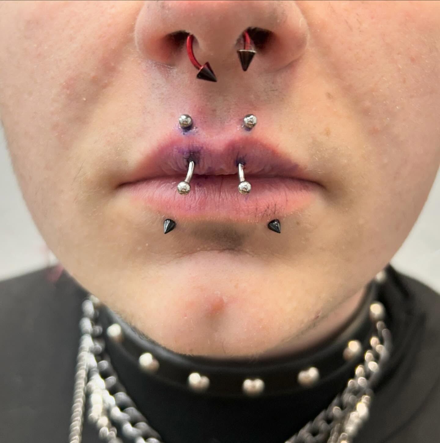 A close up of a person 's face with multiple piercings