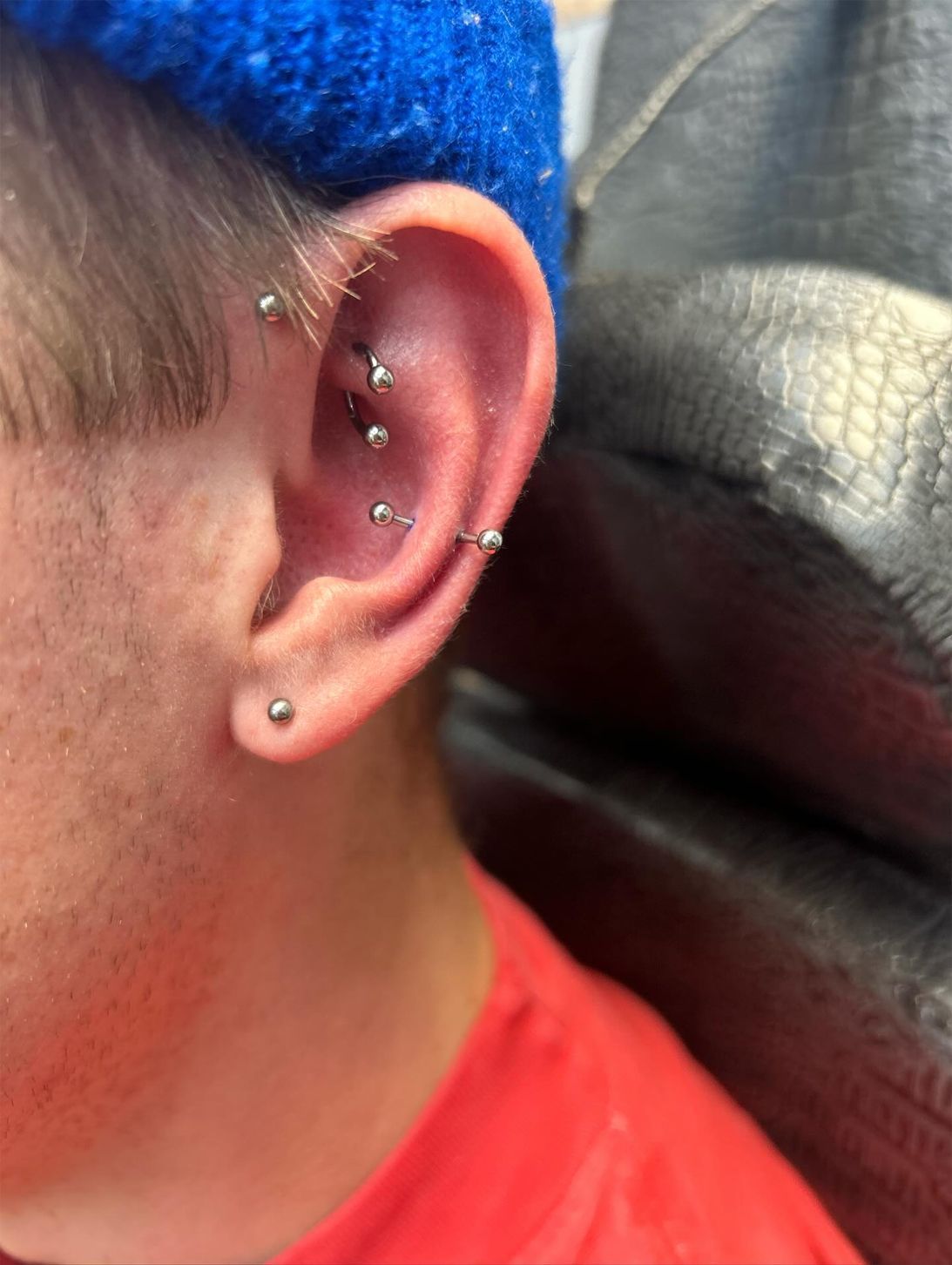 A close up of a person 's ear with multiple piercings.