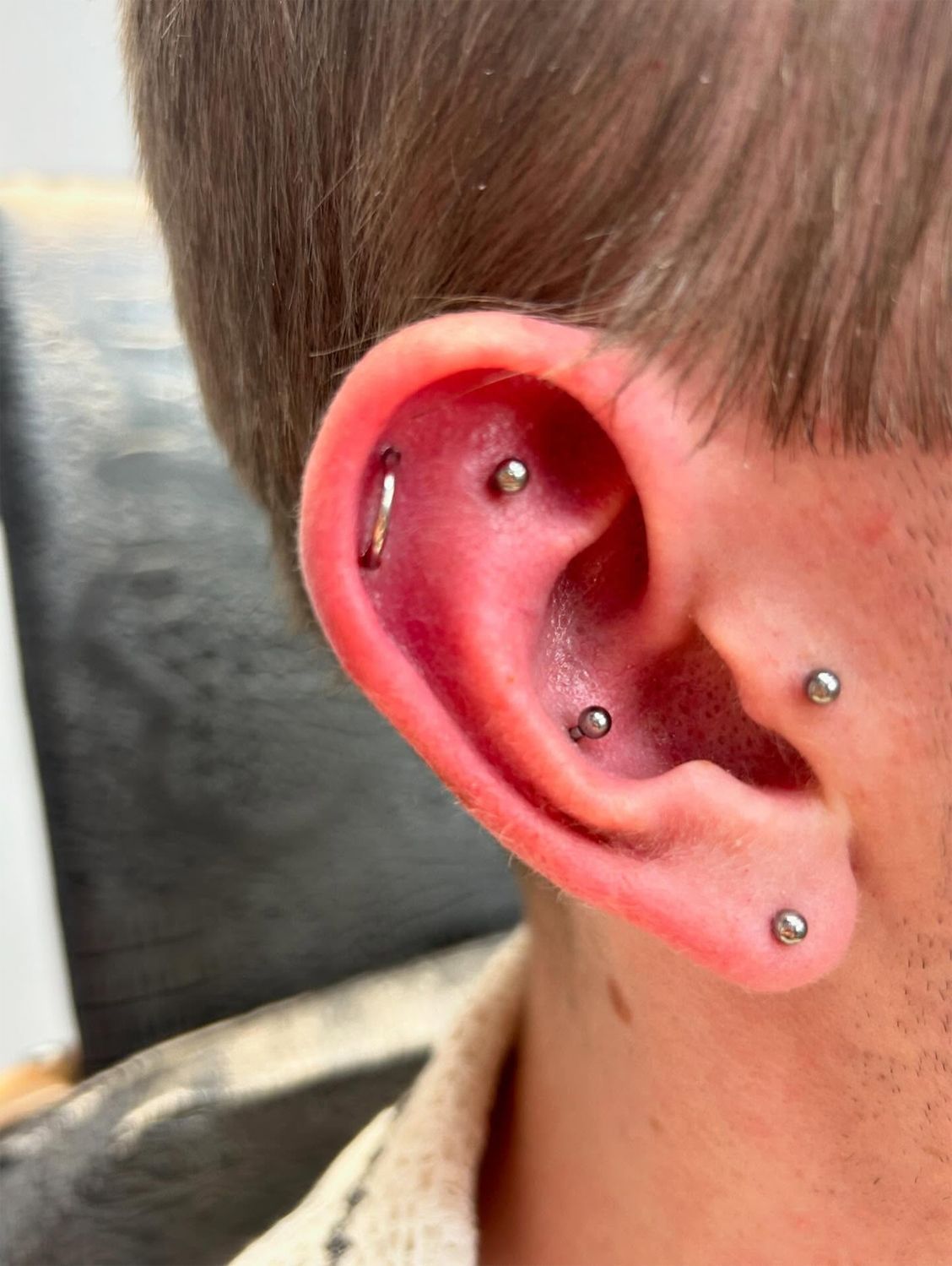 A close up of a person 's ear with multiple piercings.