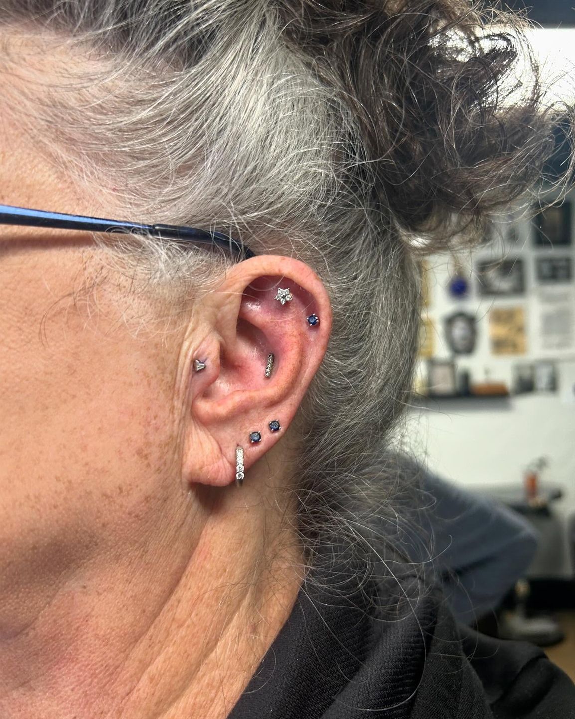 A close up of a woman 's ear with multiple piercings.
