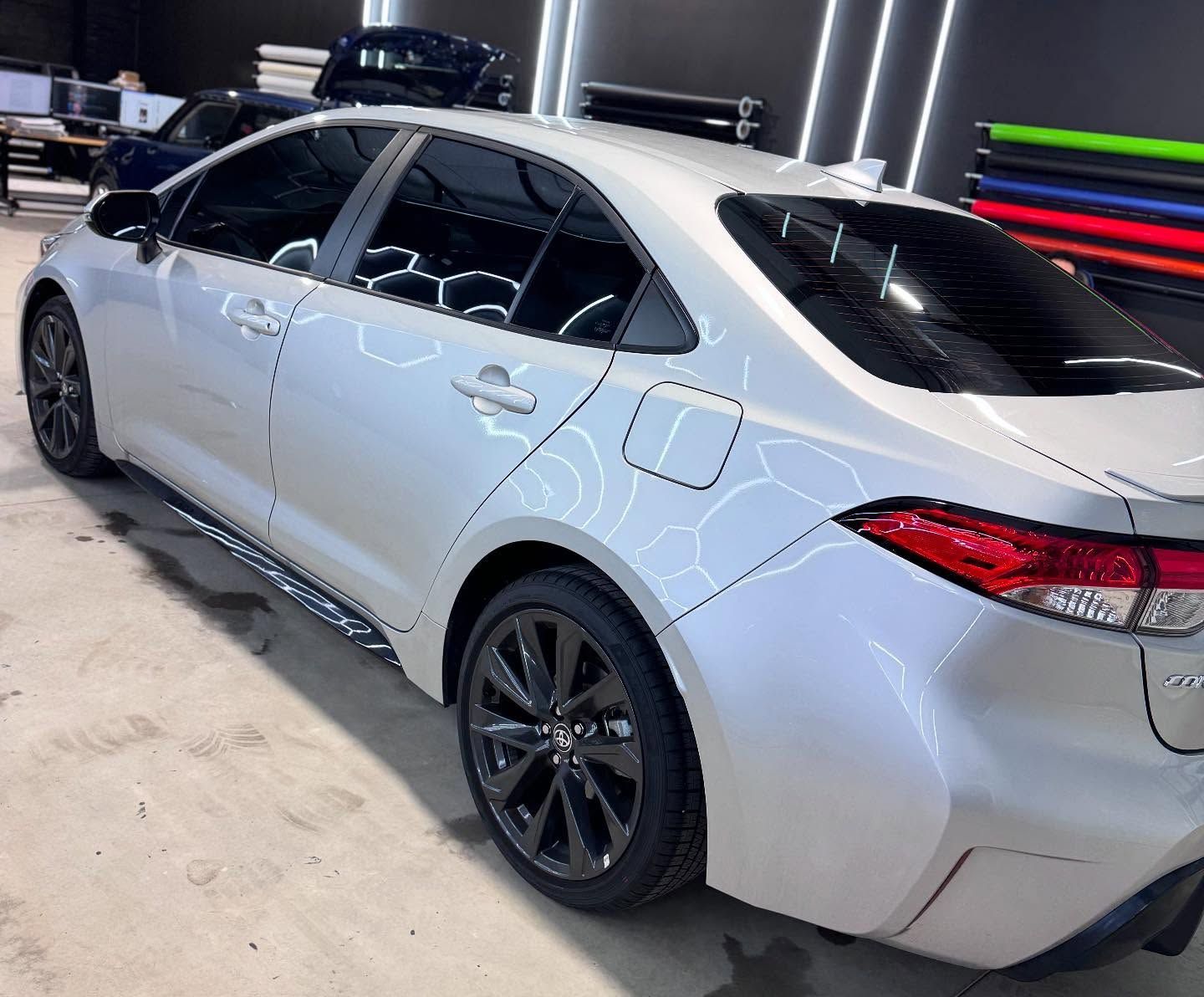 A white toyota corolla is parked in a garage.