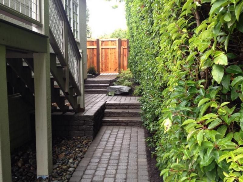 A brick walkway leading to a wooden gate and stairs