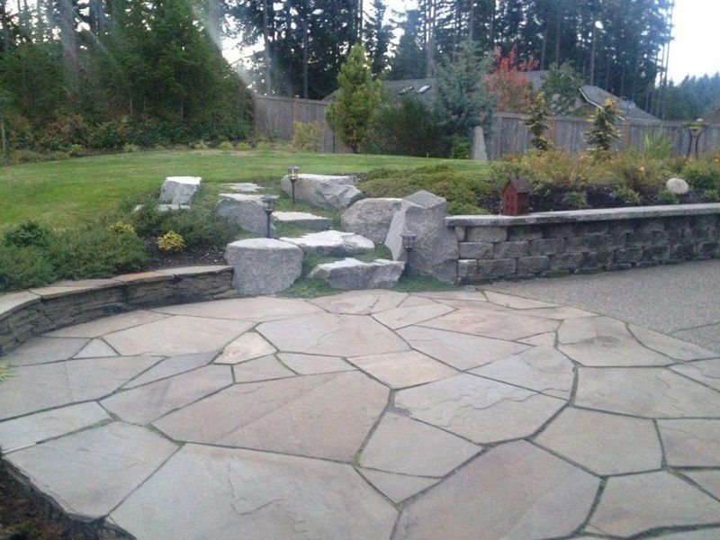 A stone patio in a backyard with trees in the background