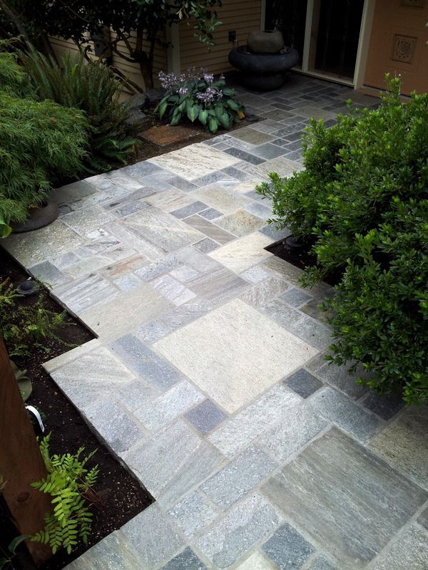 A stone walkway leading to a house with a fountain in the background