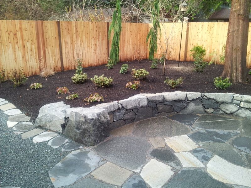 A backyard with a wooden fence and a stone walkway