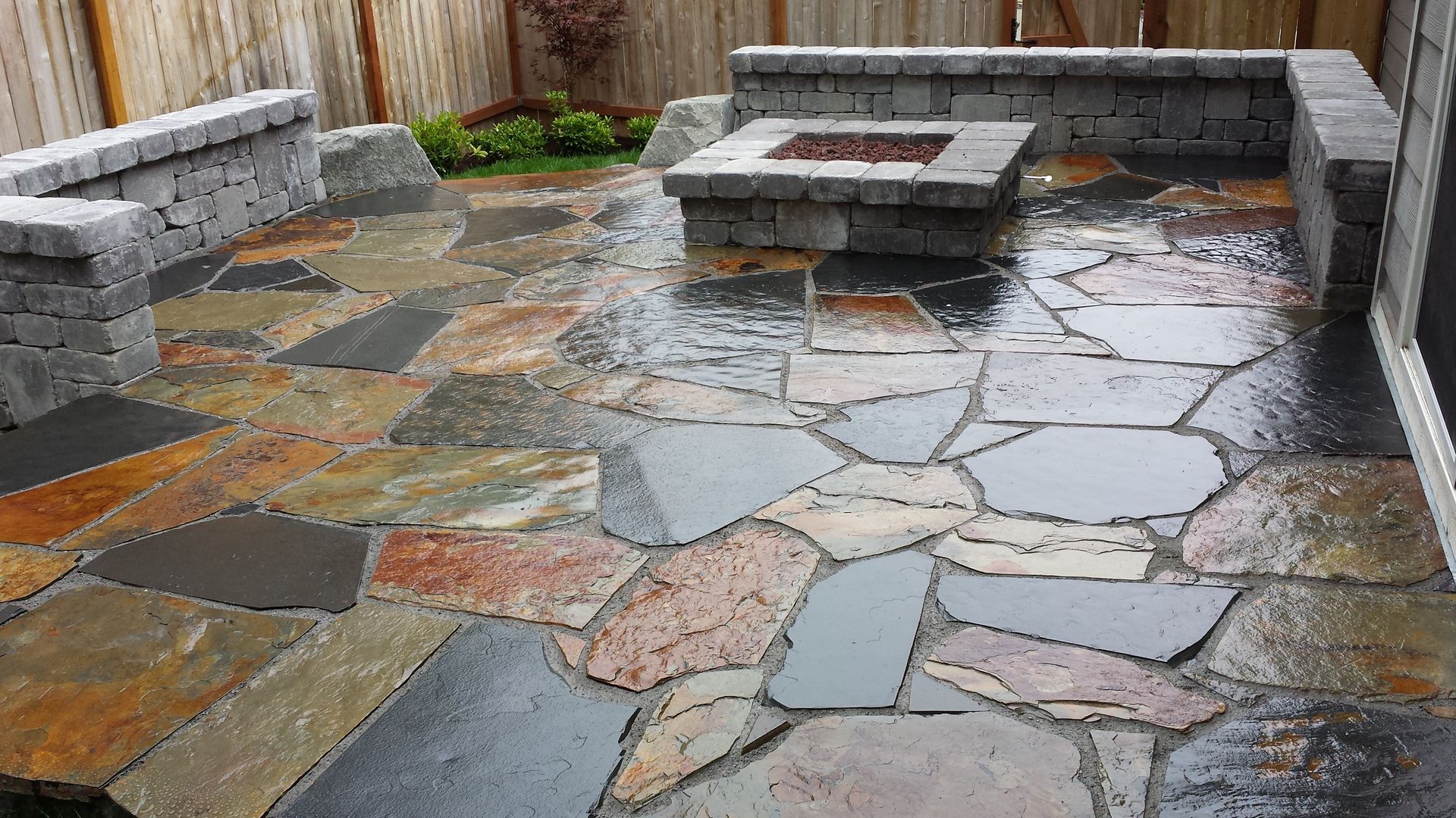 A stone patio with a fire pit in the middle of it.