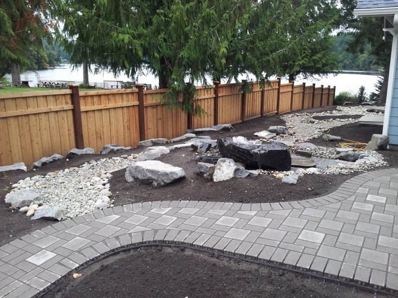 A backyard with a wooden fence and a brick walkway