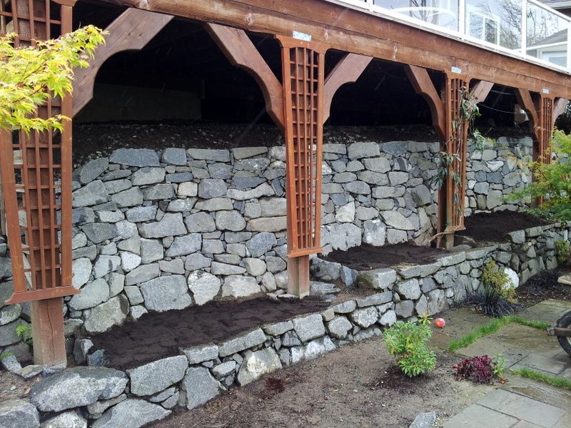 A stone wall with a wooden pergola underneath it