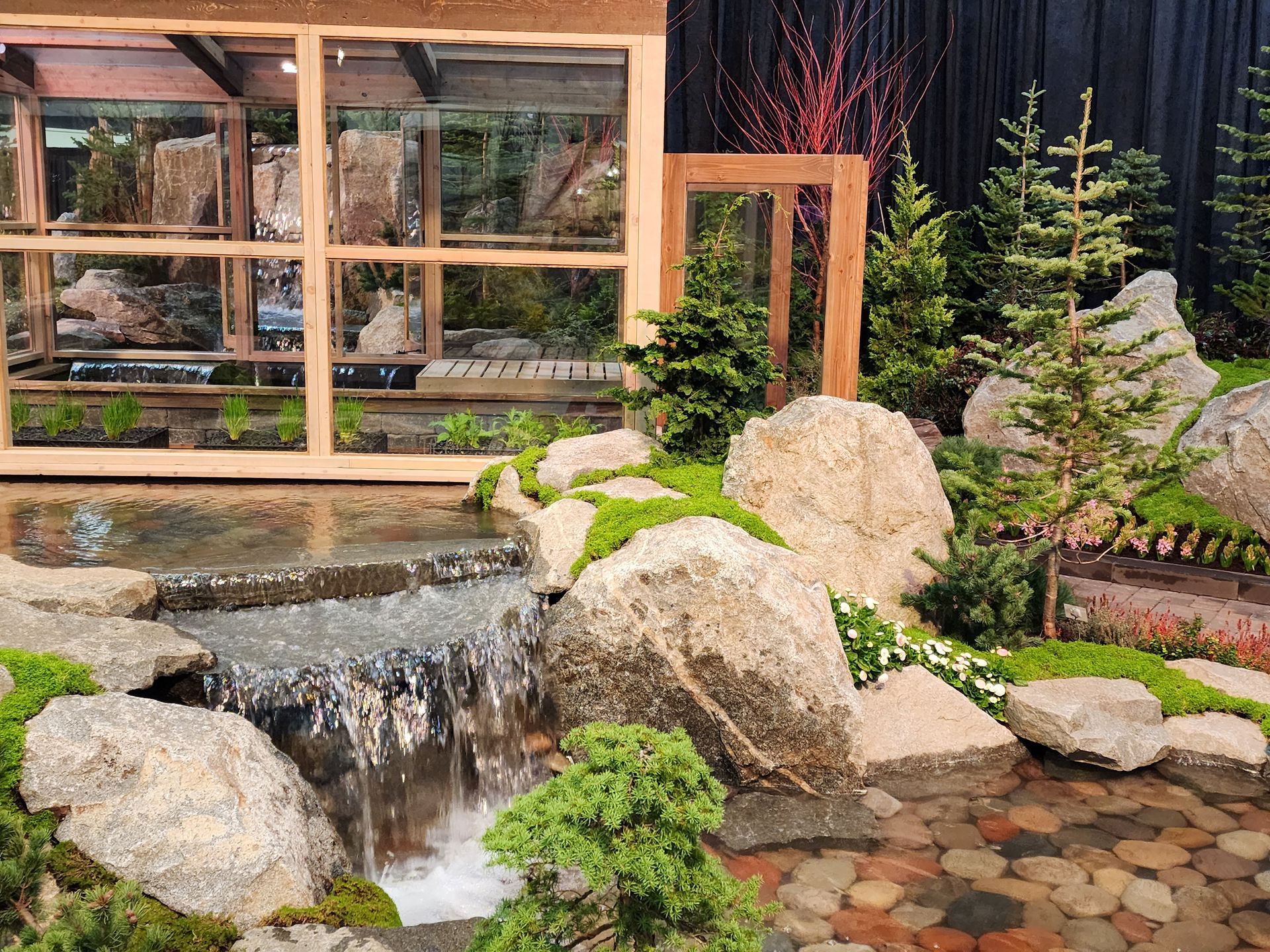 A waterfall in a garden with a house in the background
