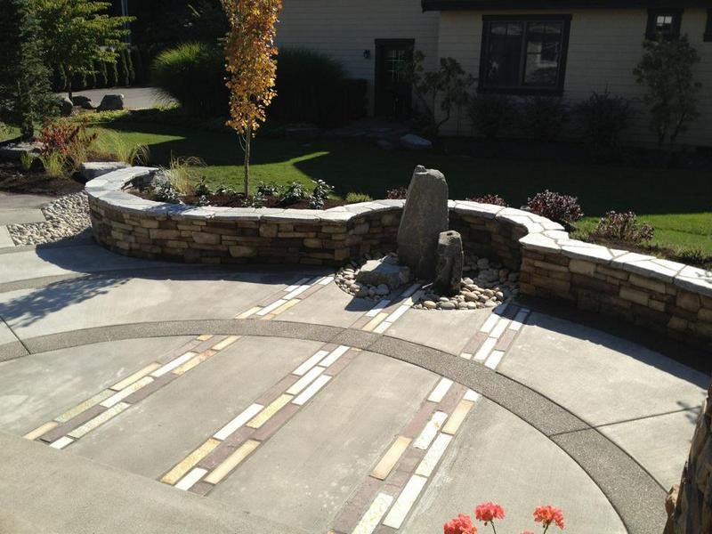 A circular patio with a stone wall and a fountain