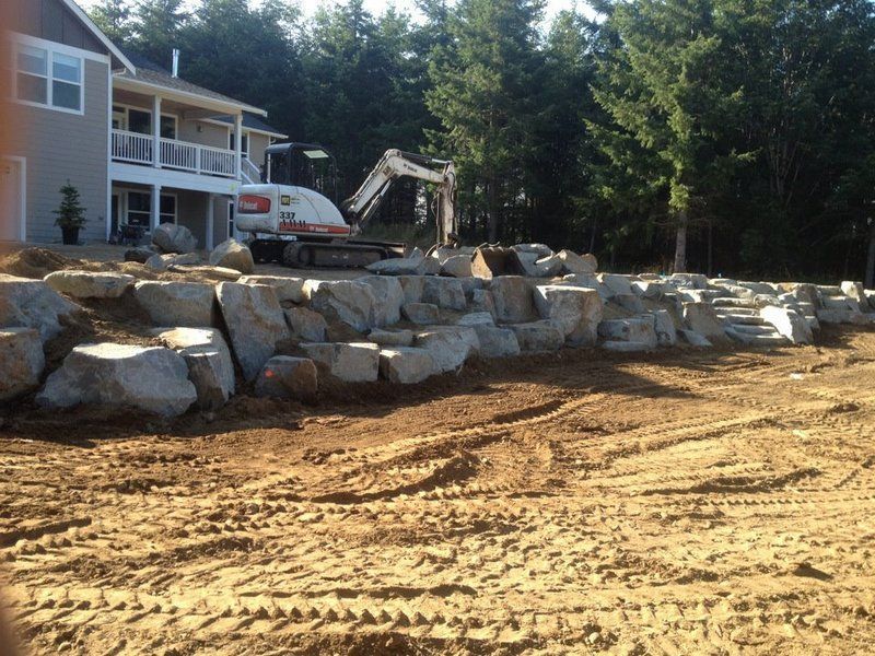 A large rock wall is being built in front of a house