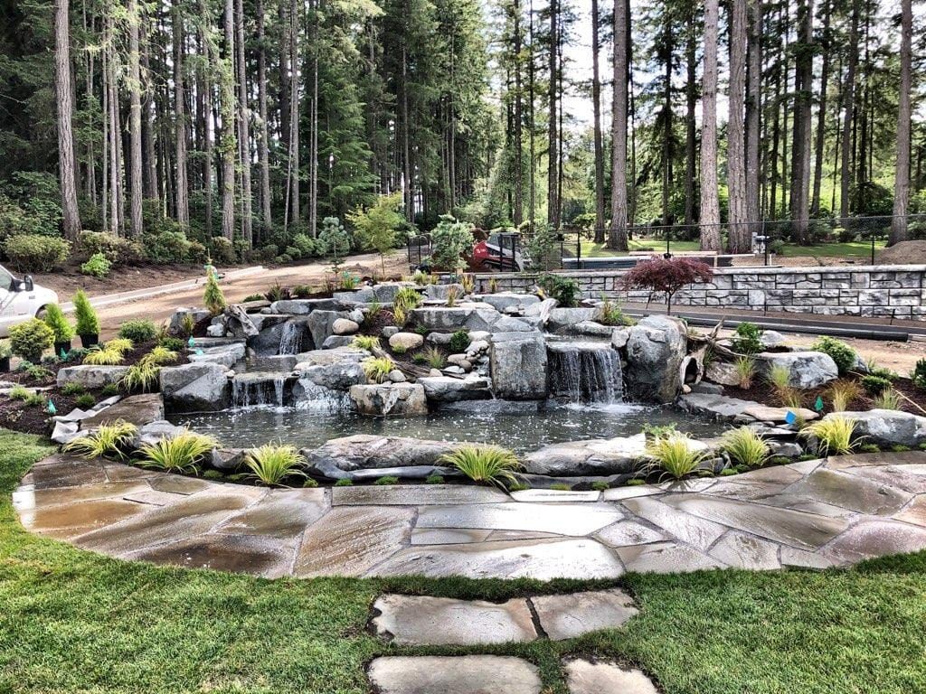 There is a waterfall in the middle of the garden surrounded by trees.