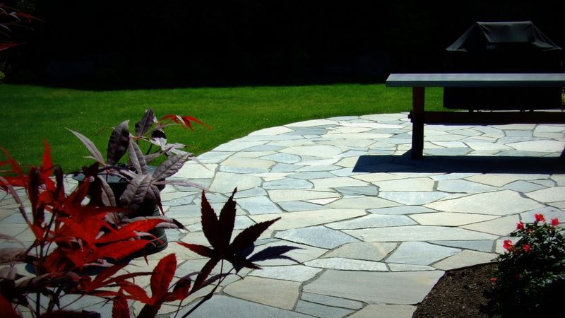 A stone patio with a grill in the background