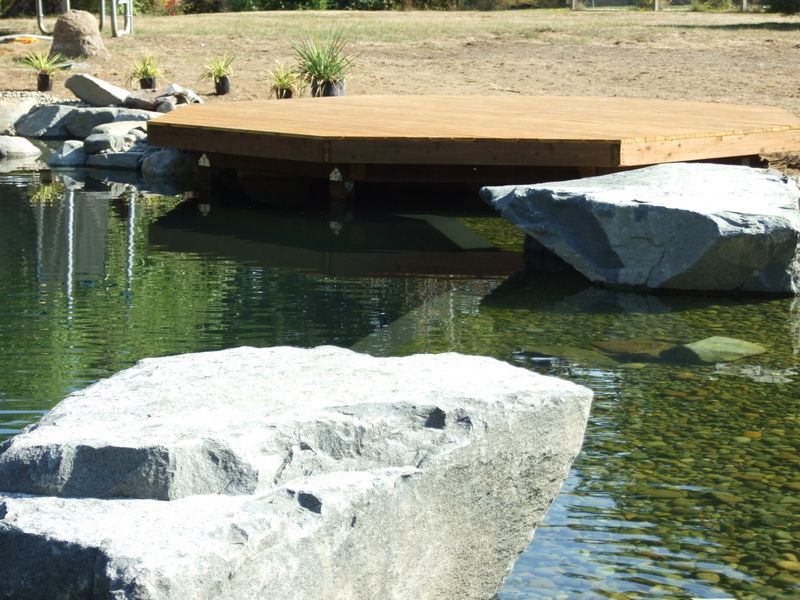 A wooden bridge over a pond surrounded by rocks