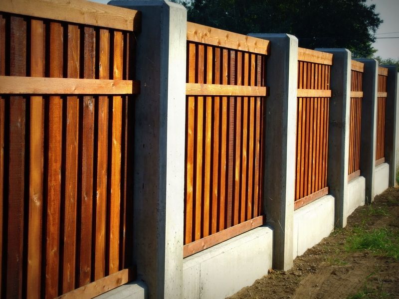 A wooden fence is surrounded by concrete pillars