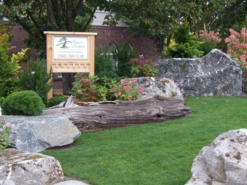 A wooden sign in a garden with a phone number