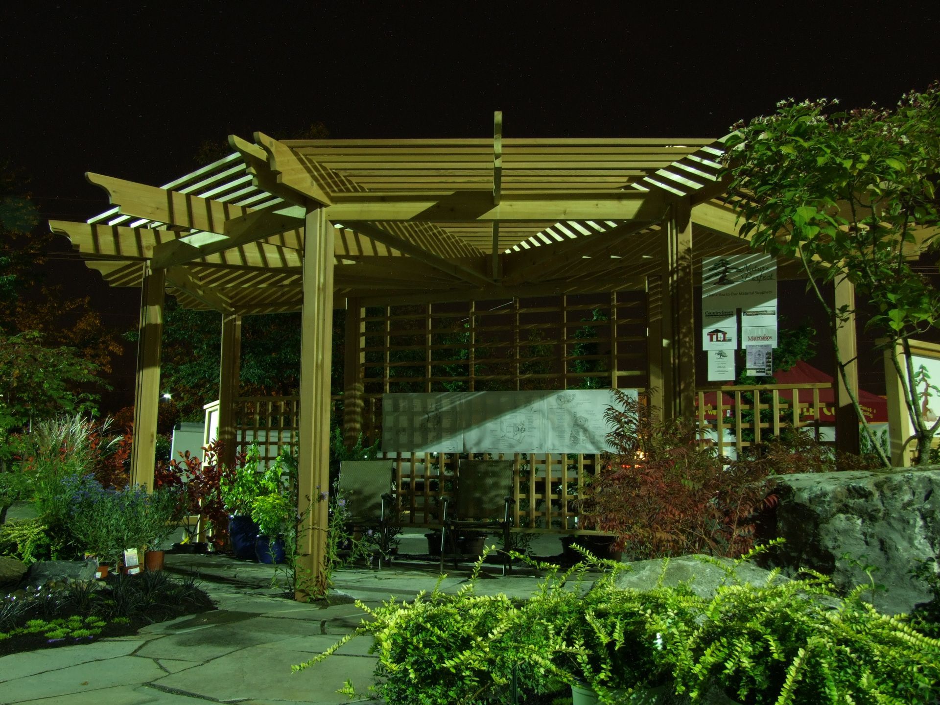 A pergola is lit up at night in a garden