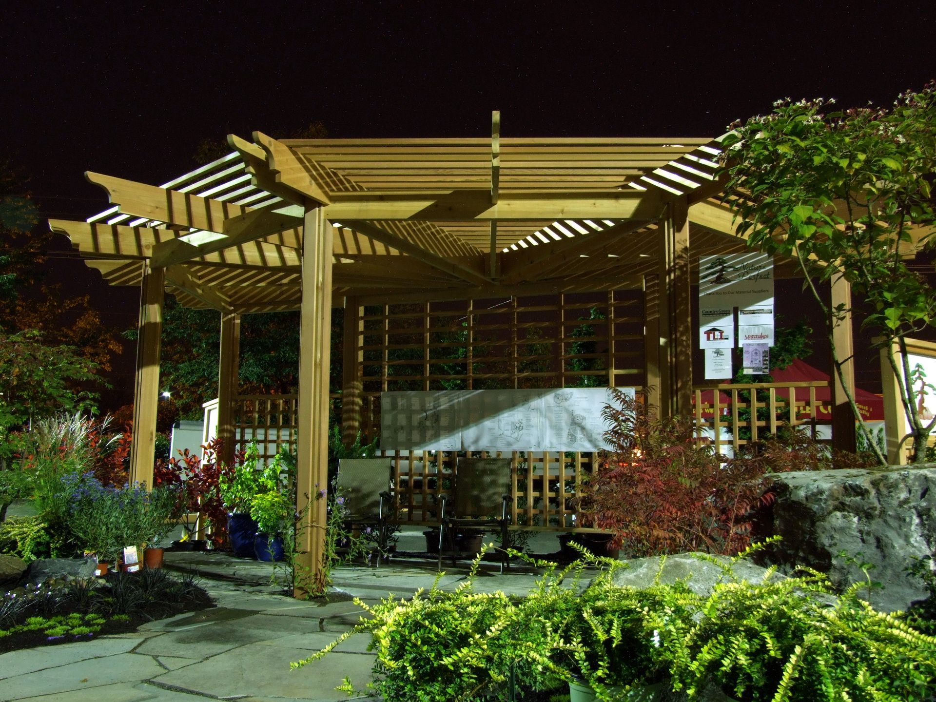A pergola is lit up at night in a garden