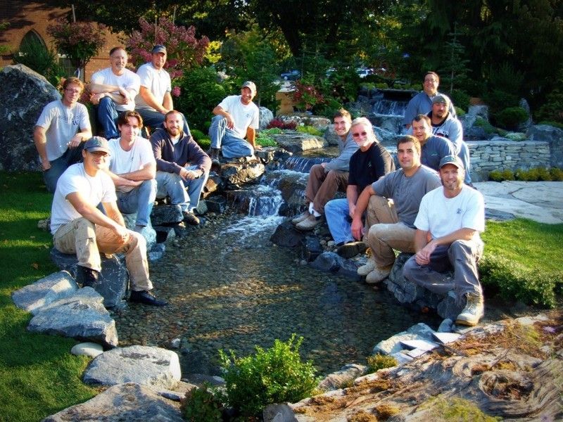 A group of men are posing for a picture in front of a waterfall
