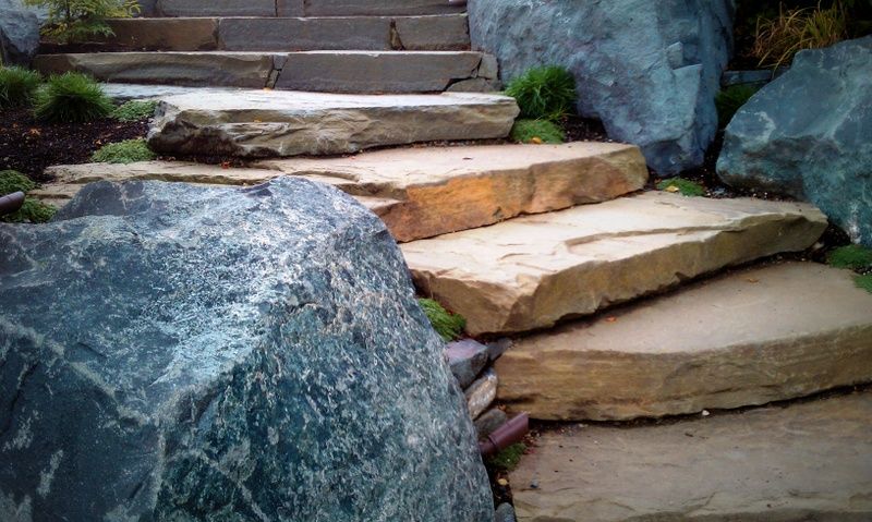 A set of stone stairs surrounded by rocks in a garden.
