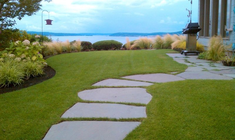 A stone walkway going through a lush green lawn