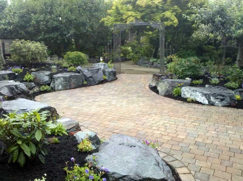 A brick walkway surrounded by rocks and flowers in a garden.