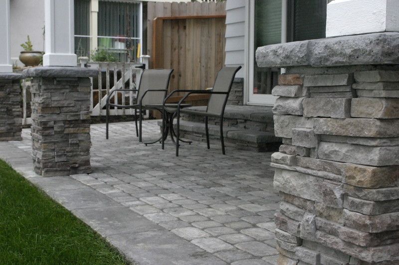 A stone patio with a table and chairs in front of a house.