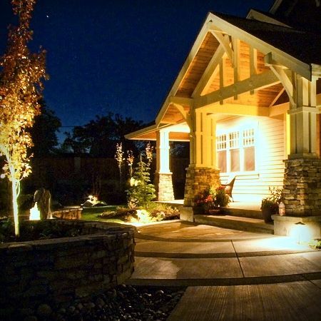 A house that is lit up at night with trees in front of it