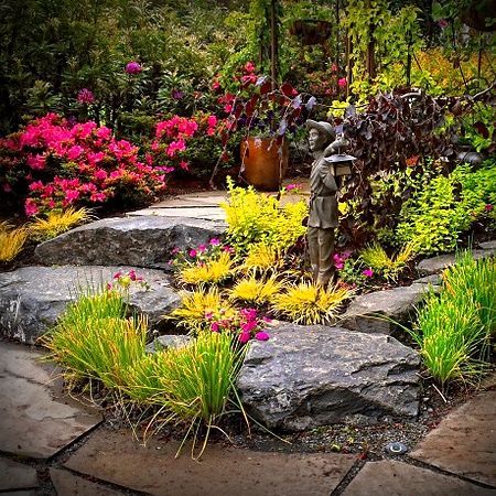 There is a statue in the middle of the garden surrounded by flowers.
