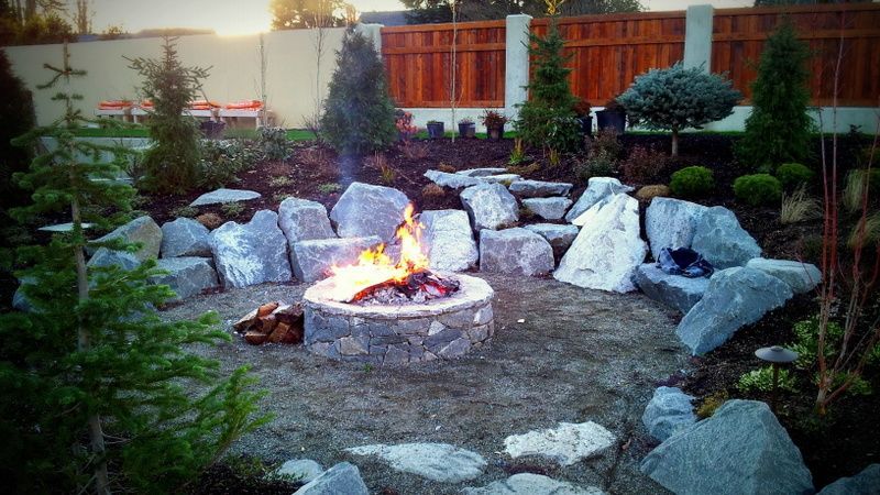 A fire pit is surrounded by rocks in a garden.