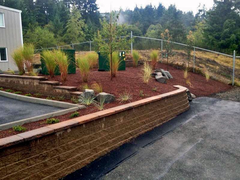 a brick wall surrounds a lush green garden with a fence