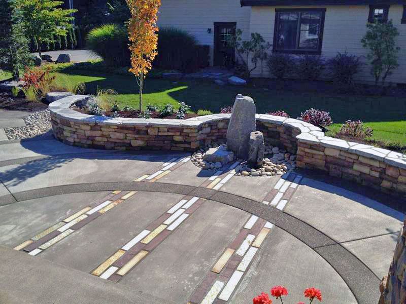 a stone wall surrounds a circular patio in front of a house